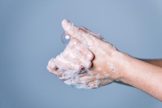 hands washing with soap foam over blue background, virus and bacteria prevention concept, horizontal photo, copy space for text