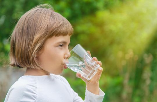 child drinks water from a glass. Selective focus.