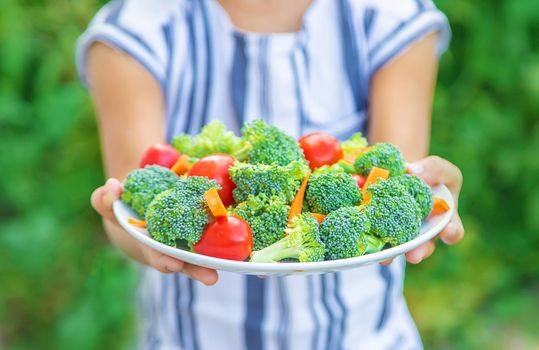 child eats vegetables broccoli and carrots. Selective focus. nature.