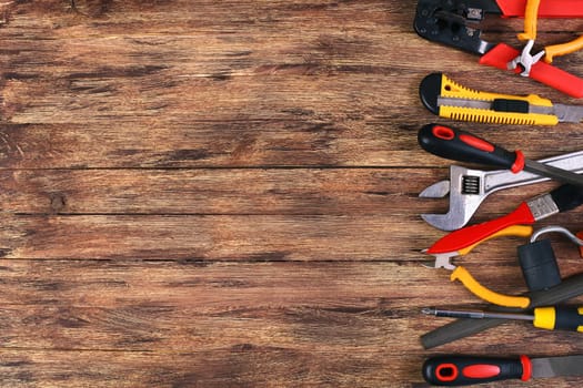 This is an overhead photo of construction tools and brush with copy space on a wood background. There is a lot of space