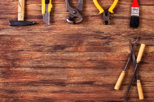 This is an overhead photo of construction tools and brush with copy space on a wood background. There is a lot of space