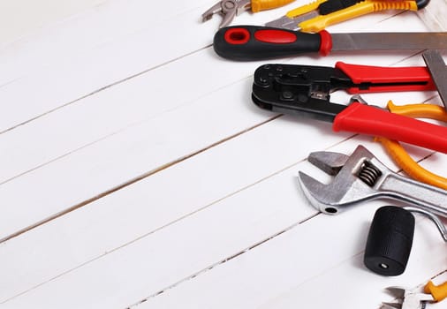 This is an overhead photo of construction tools on a white wood background. There is a lot of space for copy in the middle.