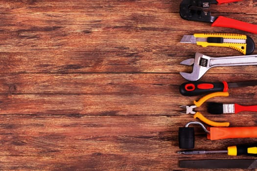 This is an overhead photo of construction tools and brush with copy space on a wood background. There is a lot of space