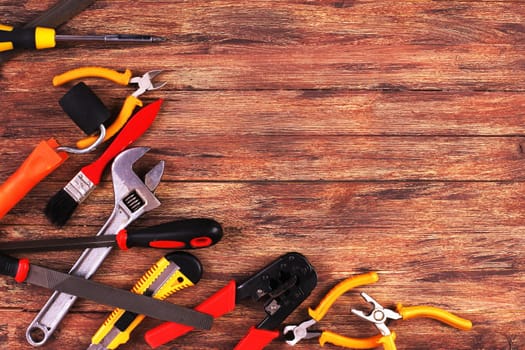 This is an overhead photo of construction tools and brush with copy space on a wood background. There is a lot of space