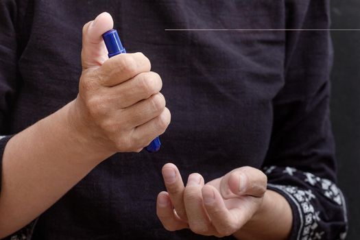 Cropped woman hands holding lancet pen to prick finger to check sugar in blood at home