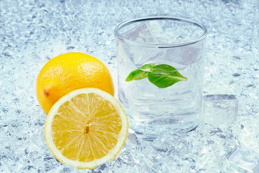 A glass of refreshing ice cold water with a lemon. On the ice background.