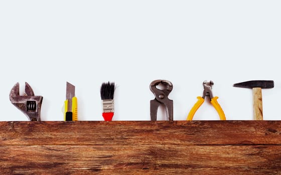 This is an overhead photo of construction tools and brush with copy space on a wood background. There is a lot of space