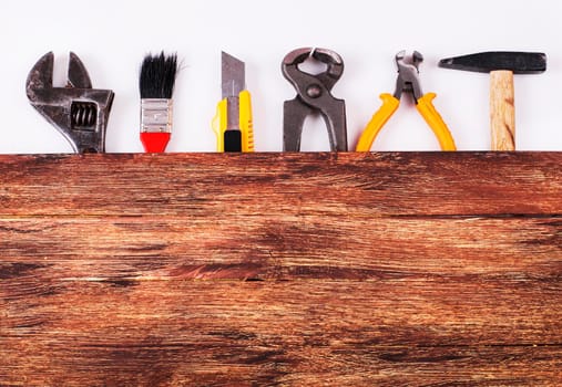 This is an overhead photo of construction tools and brush with copy space on a wood background. There is a lot of space