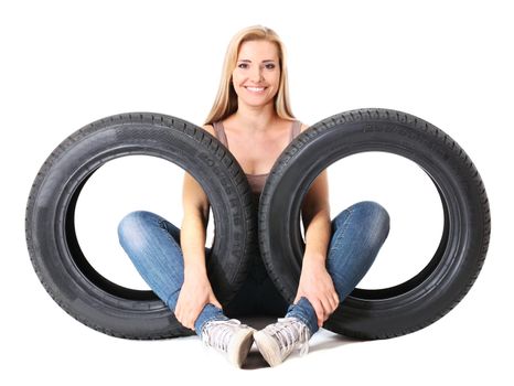 Young sexy girl sitting near the car wheels, isolated on white.