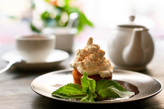 Breakfast time . Tea and cake with cream, garnished with mint leaves