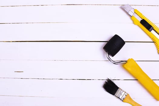 This is an overhead photo of construction tools on a white wood background. There is a lot of space for copy in the middle.