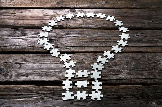 light bulb Lamp made of blank puzzle pieces on a textured wooden table.