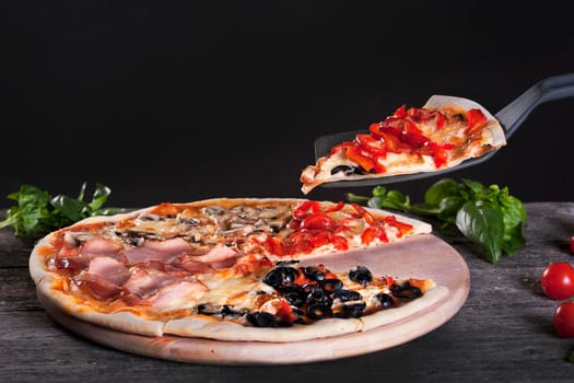 Assorted 4 parts Delicious fresh Pizza with bacon, mushrooms, peppers and olives on the wooden background. Top view.