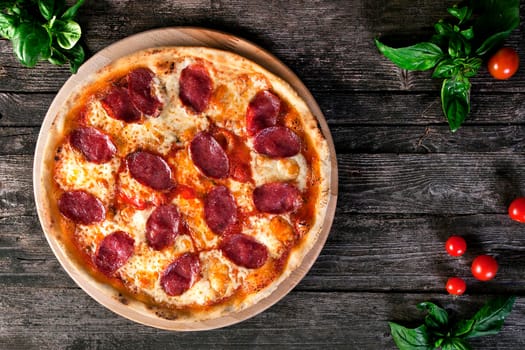 Delicious fresh Pepperoni pizza with salami and cheese on the wooden background. Top view.