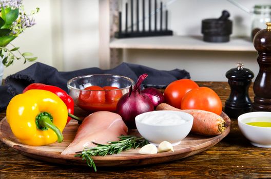 Rabbit or chicken breasts with fresh healthy vegetables, oil and spices. Raw products on the wooden background - Stock image