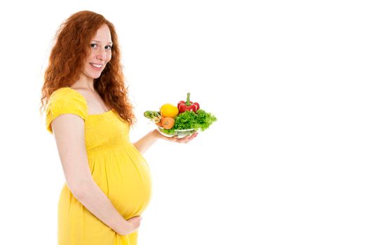 Pregnant woman holding a bowl of vegetables and smiling. Isolated on white.