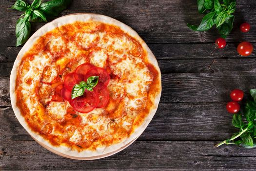 Delicious fresh margharita Pizza on the wooden background. Top view.