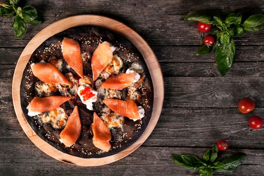 Black pizza with red fish salmon and cream cheese . Base with cuttlefish ink.