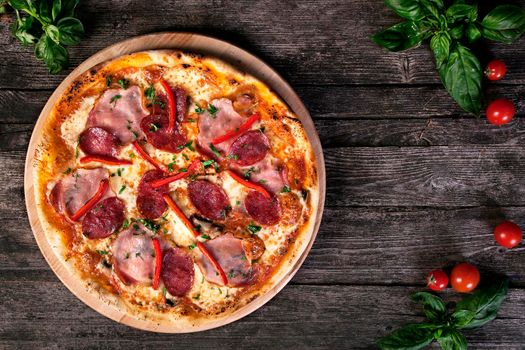 Delicious fresh Pepperoni pizza with salami , bacon , red pepper, green onions and cheese on the wooden background. Top view.