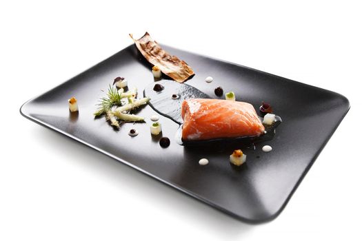 Molecular modern cuisine red fish in a dish with beautiful garnish close up. Isolated