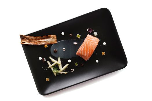 Molecular modern cuisine red fish in a dish with beautiful garnish close up. Isolated