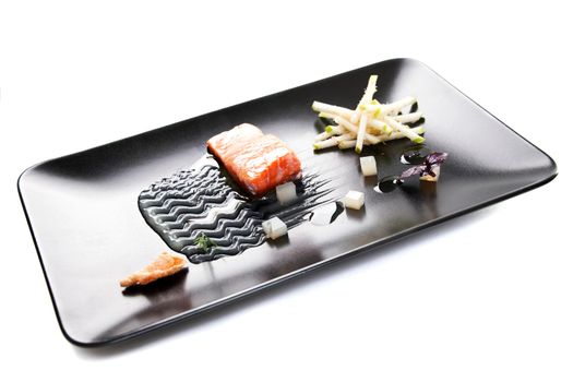 Molecular modern cuisine red fish in a dish with beautiful garnish close up. Isolated