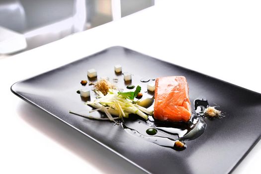 Molecular modern cuisine red fish in a dish with beautiful garnish close up. Isolated