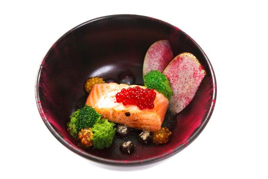 Molecular modern cuisine red fish in a dish with beautiful garnish close up. Isolated