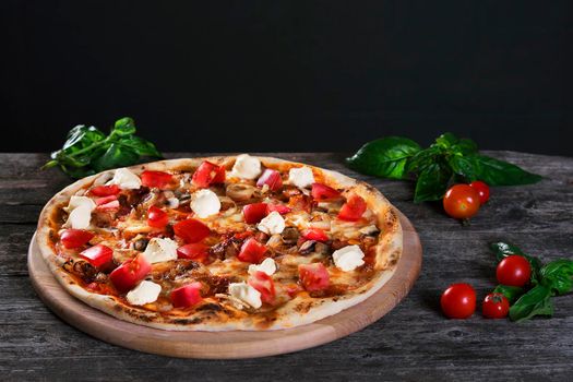 Delicious fresh Pizza with mozzarella, tomatoes, mushrooms, peppers and onion on the wooden table background. Top view.