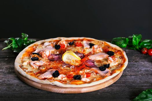 Delicious fresh Pizza with red fish and mozzarella on the wooden background. Top view.