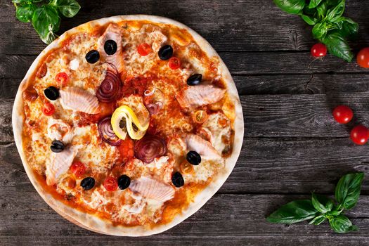 Delicious fresh Pizza with red fish and mozzarella on the wooden background. Top view.