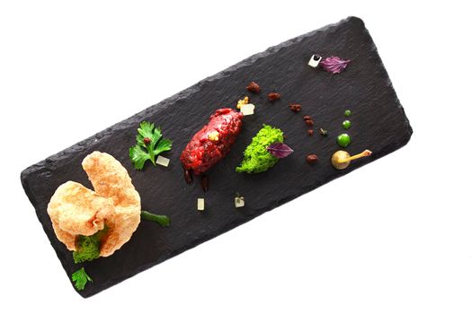 Molecular modern cuisine. Chips Pigskin with tartare or carpaccio of beef. Stock image. Isolated on white.