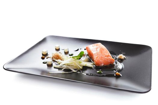 Molecular modern cuisine red fish in a dish with beautiful garnish close up. Isolated