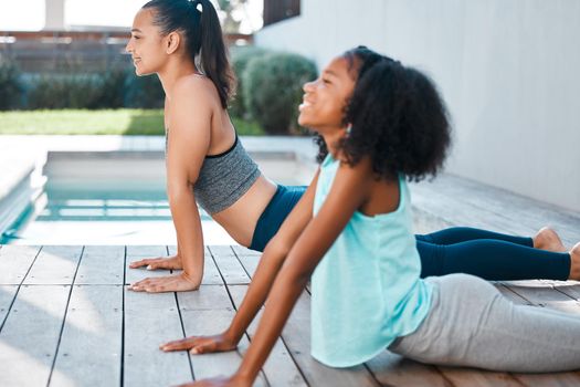 Shot of a young mother and daughter practicing yoga outside.
