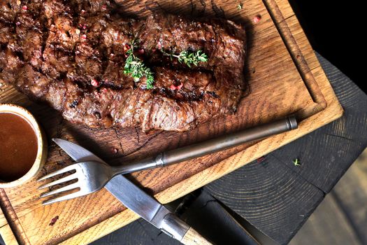 Beef steak. Piece of Grilled BBQ beef marinated in spices and herbs on a rustic wooden board over rough wooden desk with a copy space. Top view