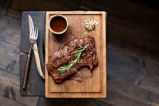 Beef steak. Piece of Grilled BBQ beef marinated in spices and herbs on a rustic wooden board over rough wooden desk with a copy space. Top view