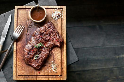 Beef steak. Piece of Grilled BBQ beef marinated in spices and herbs on a rustic wooden board over rough wooden desk with a copy space. Top view