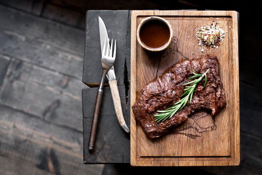 Beef steak. Piece of Grilled BBQ beef marinated in spices and herbs on a rustic wooden board over rough wooden desk with a copy space. Top view