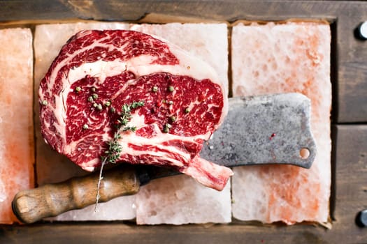 Bone In Rib Eye row Steak on pieces of salt on a wooden board. Stock image