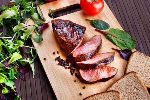 Close-up of Medium Rare Roast Beef with Fresh Herbs and Vegetables