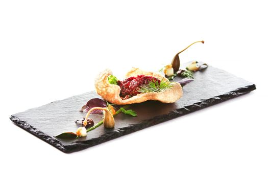 Molecular modern cuisine. Chips Pigskin with tartare or carpaccio of beef. Stock image. Isolated on white.