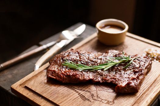 Beef steak. Piece of Grilled BBQ beef marinated in spices and herbs on a rustic wooden board over rough wooden desk with a copy space. Top view