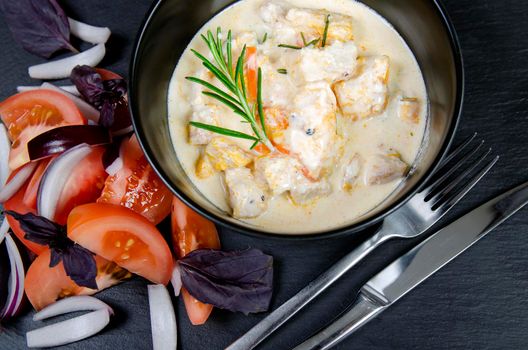 Braise fillet slices of turkey, chicken in a creamy sauce with vegetables. Black background.