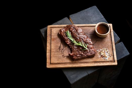 Beef steak. Piece of Grilled BBQ beef marinated in spices and herbs on a rustic wooden board over rough wooden desk with a copy space. Top view. Stock Image