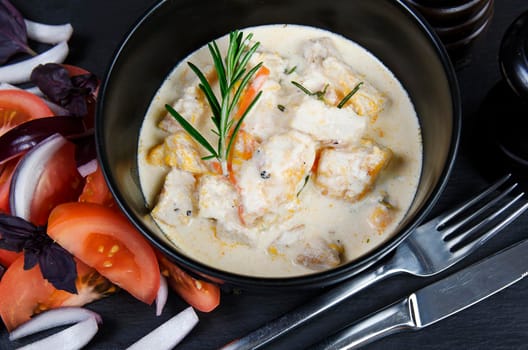 Braise fillet slices of turkey, chicken in a creamy sauce with vegetables. Black background.