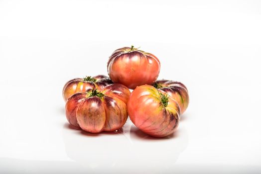 Several tomatoes of the tiger variety on a white background