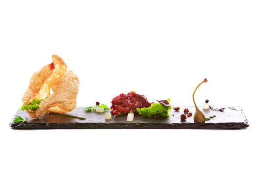 Molecular modern cuisine. Chips Pigskin with tartare or carpaccio of beef. Stock image. Isolated on white.