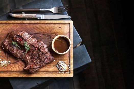 Beef steak. Piece of Grilled BBQ beef marinated in spices and herbs on a rustic wooden board over rough wooden desk with a copy space. Top view. Stock Image