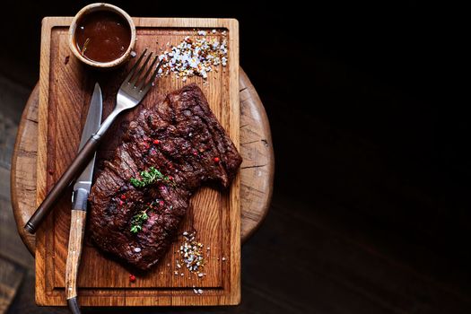 Beef steak. Piece of Grilled BBQ beef marinated in spices and herbs on a rustic wooden board over rough wooden desk with a copy space. Top view