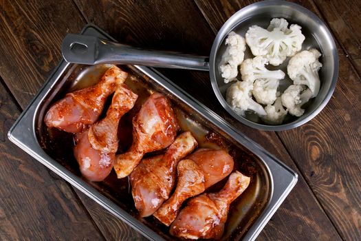 Cooking. Recipe. Baked chicken drumsticks with cauliflower served on a wooden table. Rustic style. Top view